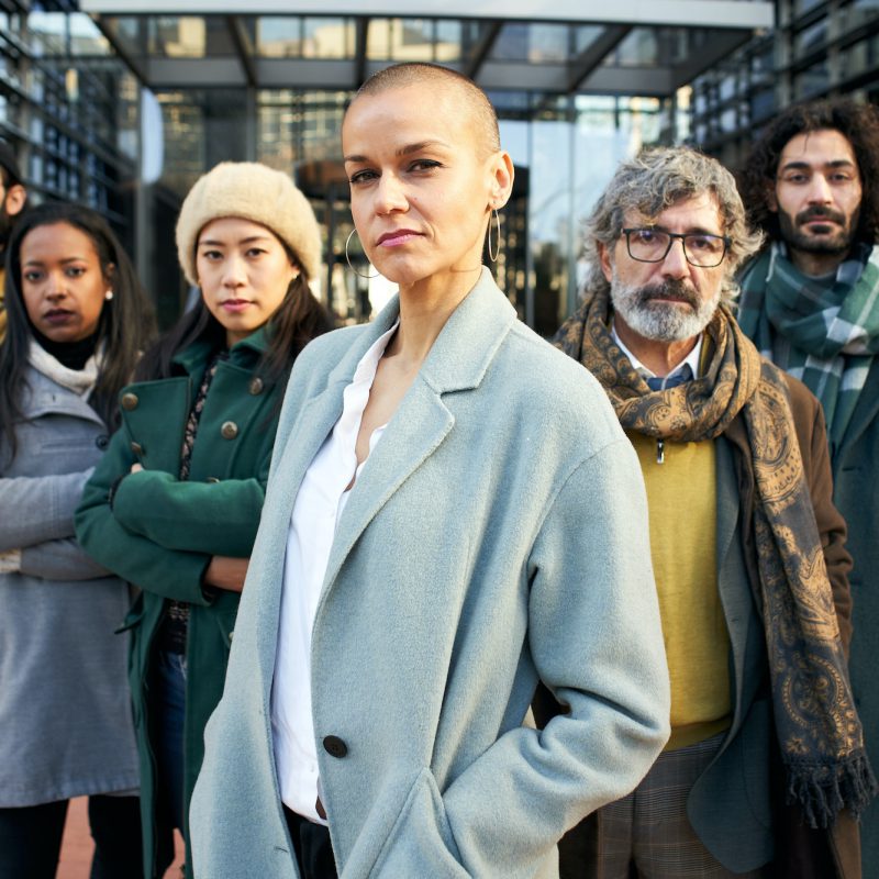 A group of serious business people from a company led by an empowered shaved air woman